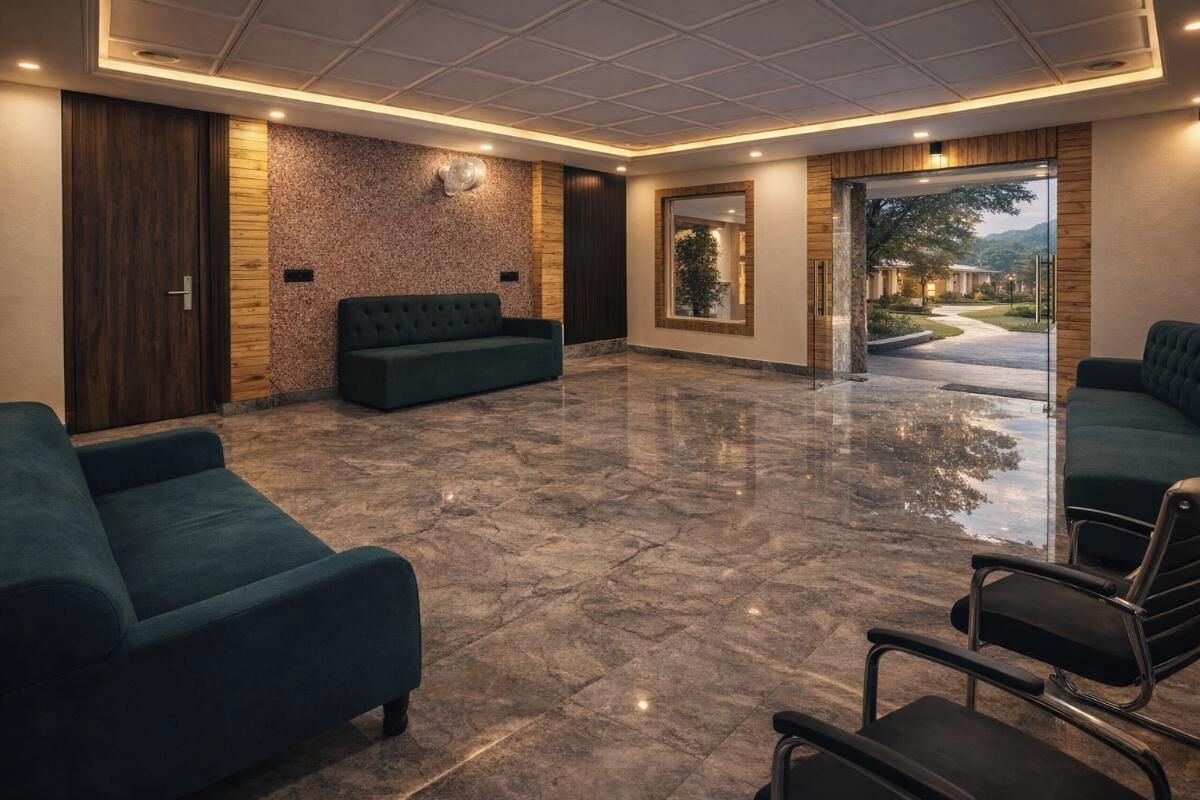 A spacious lobby with a marble floor, dark green sofas, and a large mirror reflecting the outdoor view.