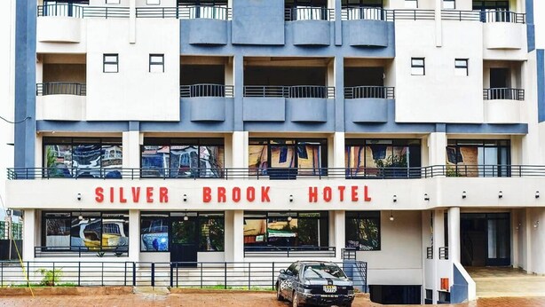A multi-story hotel with balconies and a car parked in front. - Silver Brooke Hotel Othaya (Othaya)