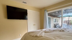 A bedroom with a bed, a TV mounted on the wall, and a view of the backyard through a window. - Cozy 4BR Home in Mountain View (Mountain View)