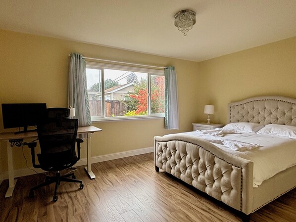 A bedroom with a bed, a desk, a chair, a window, and a chandelier. - Cozy 4BR Home in Mountain View (Mountain View)