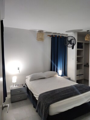 Una camera da letto con un letto, lampade da comodino, un comodino, un armadio e una ventola a soffitto.