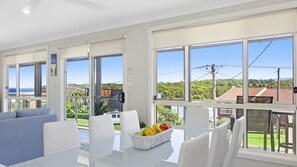 A modern living room with a dining area, large windows, and a view of the outdoors. - Sea-Renity is a spacious home (Manyana)