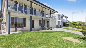A modern two-story residential building with a balcony, a front bench, and a well-maintained lawn. - Sea-Renity is a spacious home (Manyana)