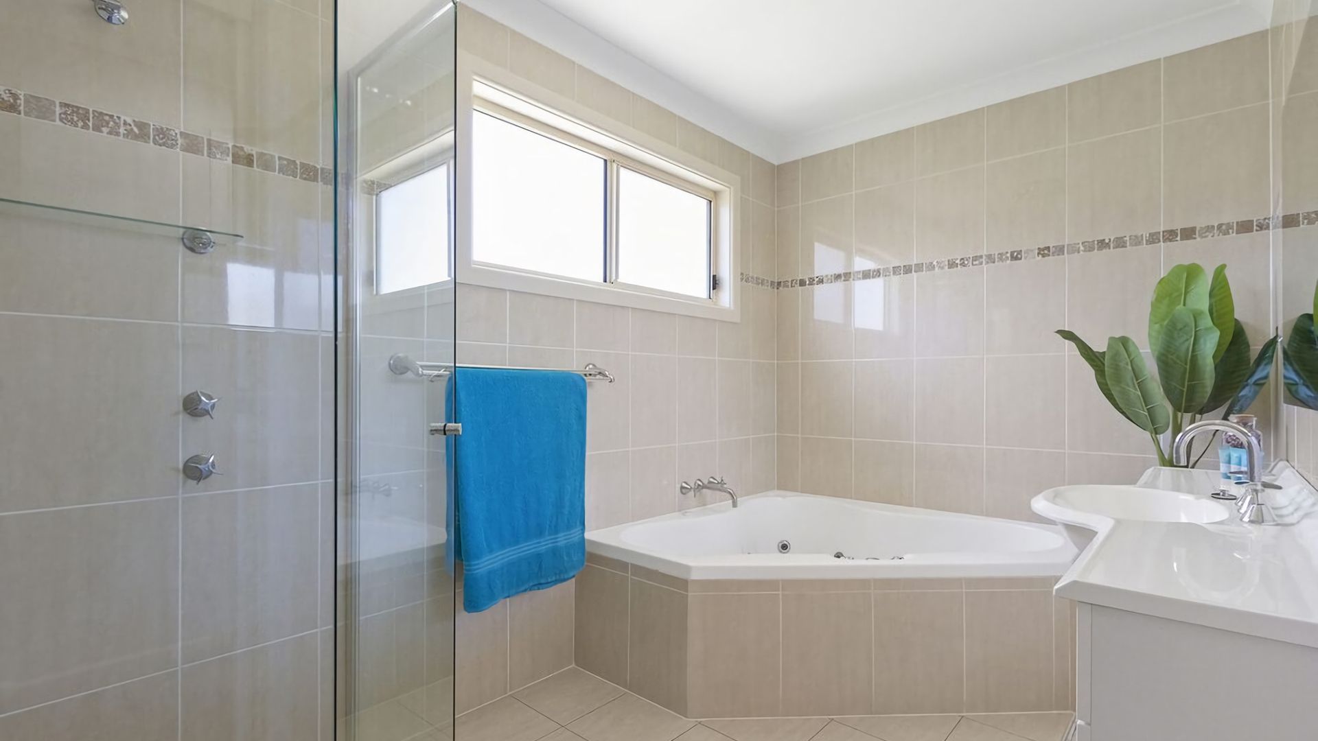 A modern bathroom with a glass shower enclosure, a bathtub, and a sink.