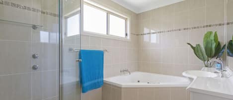 A modern bathroom with a glass shower enclosure, a bathtub, and a sink.