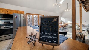 Eine moderne Küche mit Edelstahlgeräten, einer Holzinsel und einem Kreidetafel-Schild, das Gäste willkommen heißt.