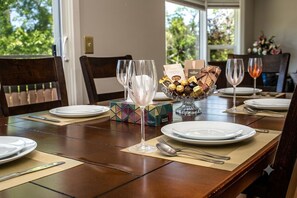 A dining table set with white plates, cutlery, and a glass of champagne. A centerpiece with chocolates and a box is on the table. - I @Home Entire 4BR3BA House/YYC/Parking/BBQ (Calgary)