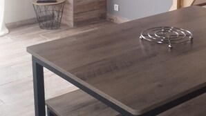 A modern dining area with a wooden table and benches, a TV mounted on the wall, and a staircase with wooden railings. - Jetez l'Ancre - Gîte pour ralentir in La Tremblade (La Tremblade)