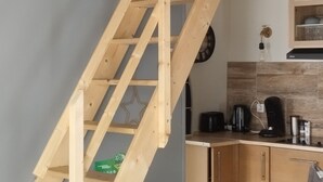 A wooden staircase leading to an upper floor, a kitchen area with a coffee maker, and a small cabinet with a decorative leaf design. - Jetez l'Ancre - Gîte pour ralentir in La Tremblade (La Tremblade)