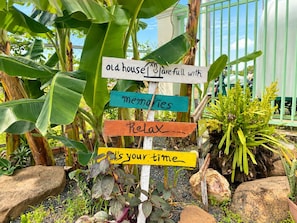 A signpost with multiple signs in a garden setting. - AHHA River Breeze Kampot  (Kampot)