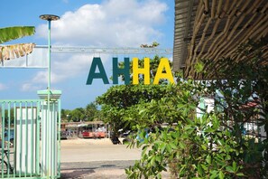 Een bord met de tekst 'AHHA' in grote letters, een metalen poort en wat groenvoorplanting op de voorgrond.