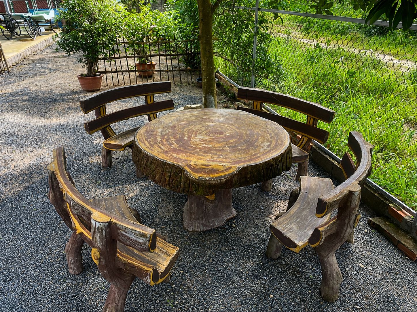 Una mesa redonda de madera con bancos, rodeada de grava.