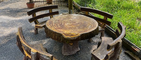 A round wooden table with benches, surrounded by gravel.