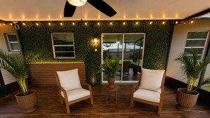A modern outdoor seating area with two wooden chairs, a small round table, and potted plants.