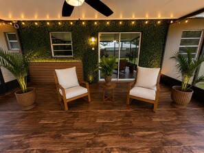 A modern outdoor seating area with two wooden chairs, a small round table, and potted plants.