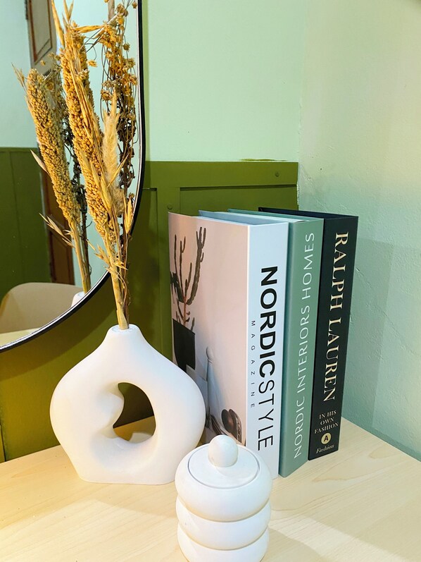 A white vase with dried plants, a white abstract sculpture, and two books titled 'Nordic Style Magazine' and 'Ralph Lauren'. - Bandung Co Stay (Bandung)