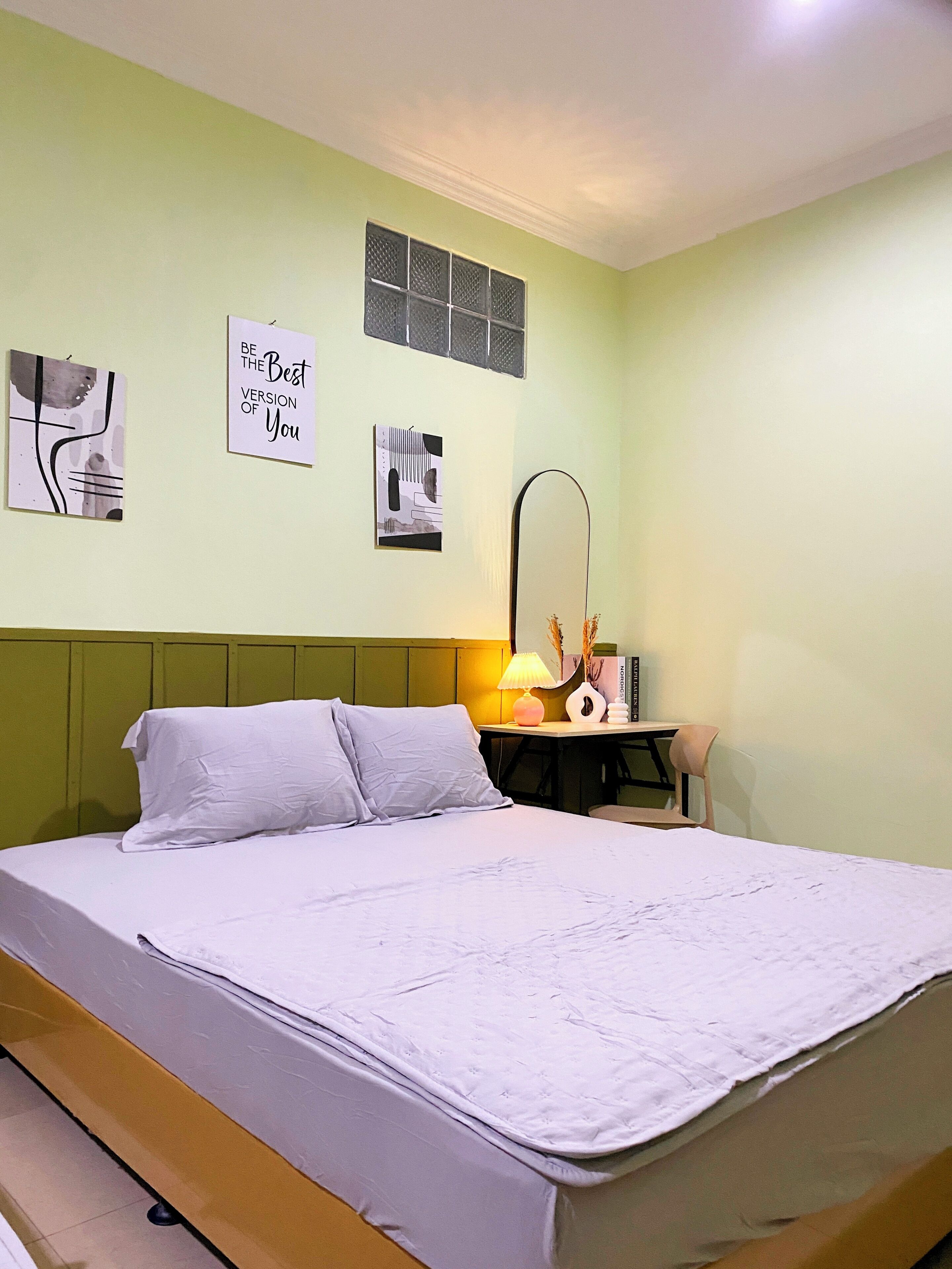 A bedroom with a bed, a desk, a chair, and two wall art pieces.