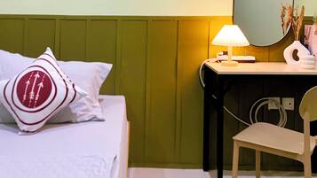 A hotel room with a bed, a desk with a lamp, a chair, and a mirror.