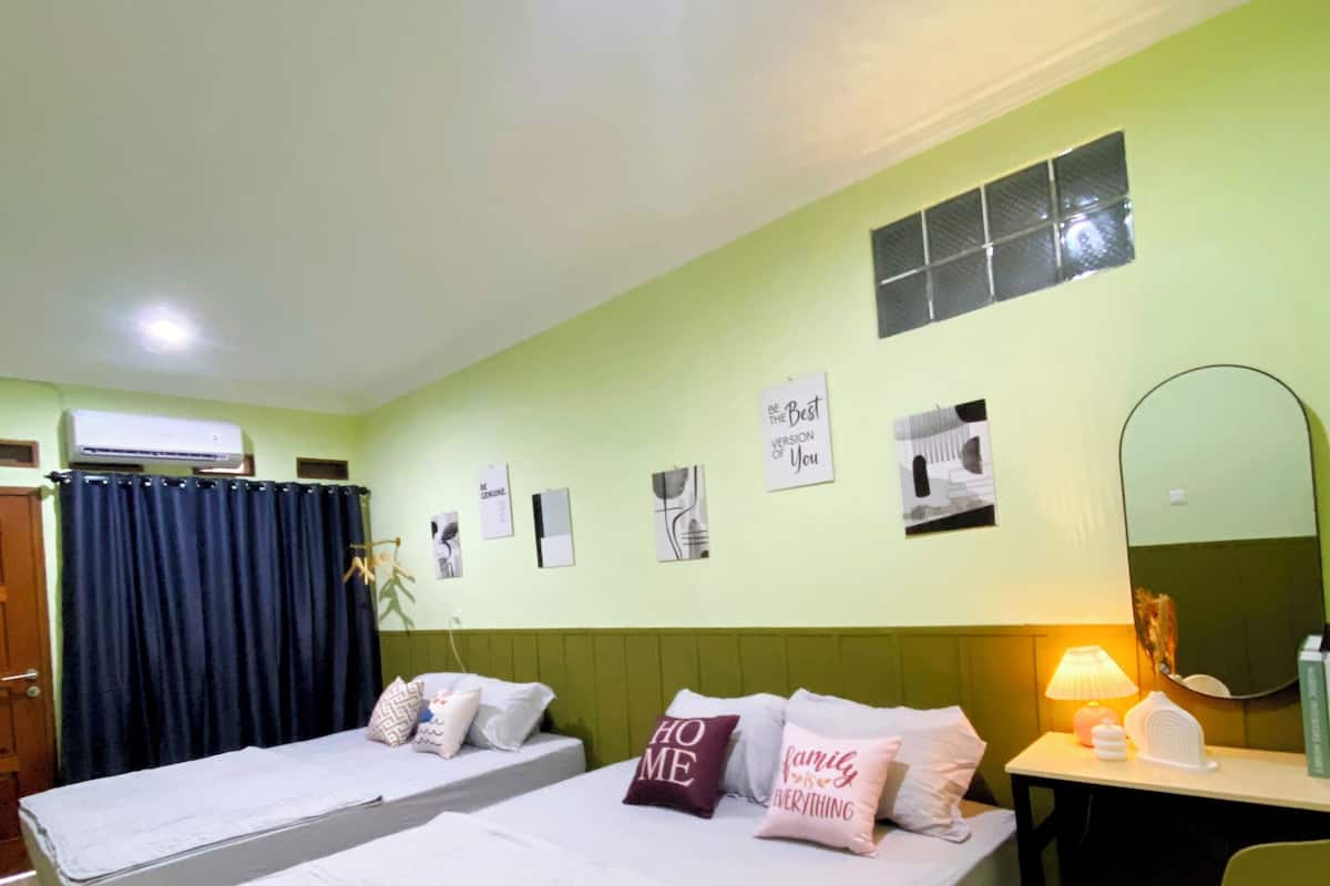 A hotel room with two single beds, a desk with a chair, a mirror, and a wall with motivational posters.