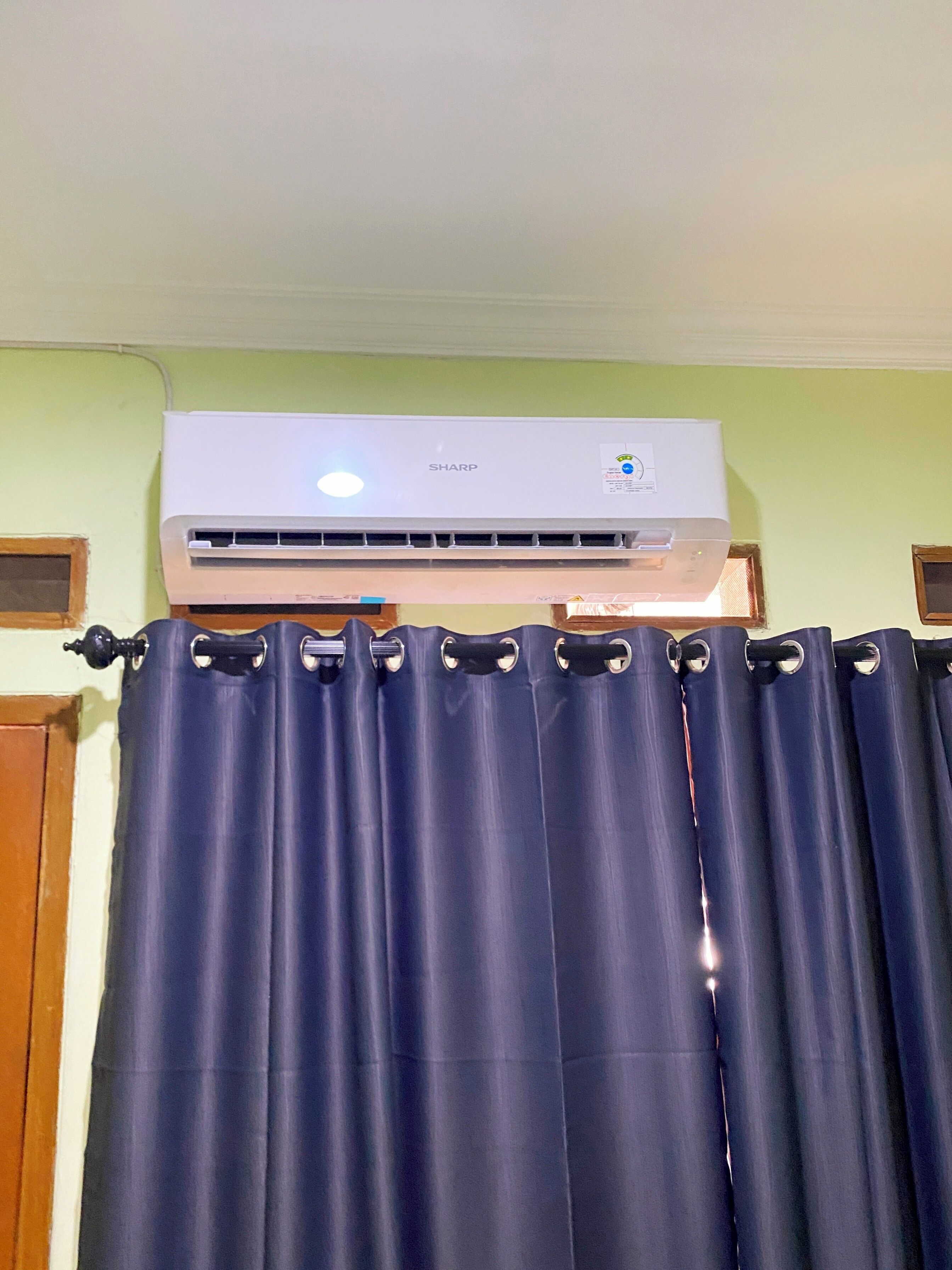 Een airconditioningunit boven een reeks donkerblauwe gordijnen.
