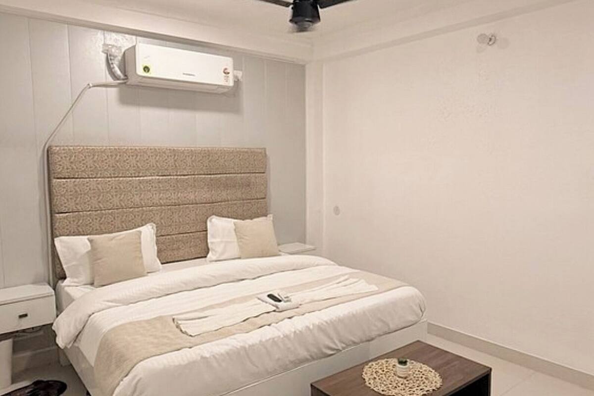 A modern bedroom with a bed, bedside tables, a ceiling fan, and an air conditioning unit.