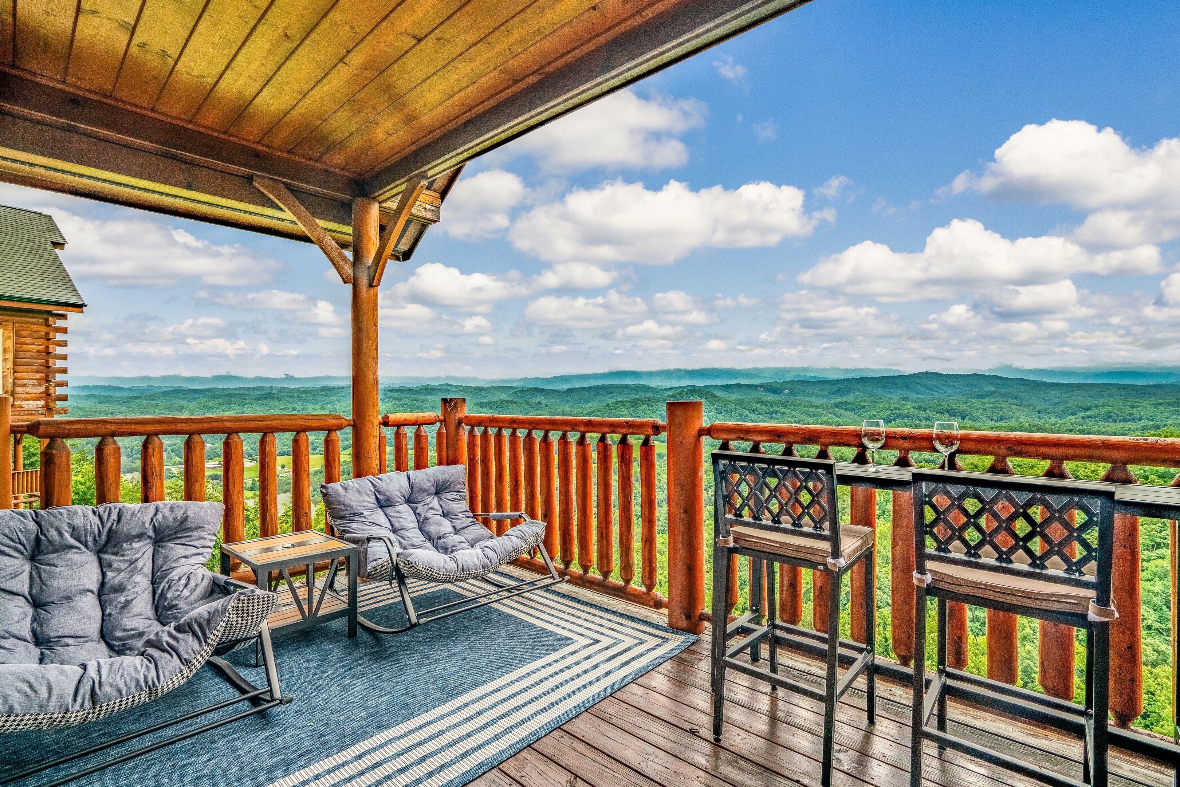 Une terrasse en bois offrant une vue sur les montagnes, un espace couvert avec des sièges et une rambarde.
