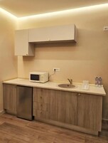 Una cocina compacta con microondas, pileta y muebles de madera.