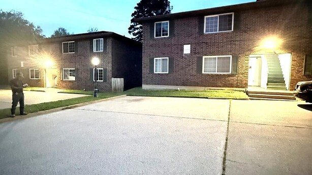 A two-story brick building with a driveway and a car parked in front.