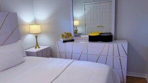 Ein Hotelzimmer mit Bett, Nachttischen, einer Lampe, einem Spiegel und einer Kommode mit Dekoration.