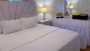 A hotel room with a large bed, a bedside lamp, a nightstand, and a mirror.