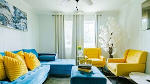 A living room with a blue sofa, yellow armchairs, and a coffee table. - Sunlit 2BR · Full Kitchen · 2 Min to SFA (Nacogdoches)