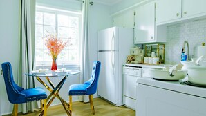 A modern kitchen with white appliances, a dining table with blue chairs, and a vase of flowers. - Sunlit 2BR · Full Kitchen · 2 Min to SFA (Nacogdoches)
