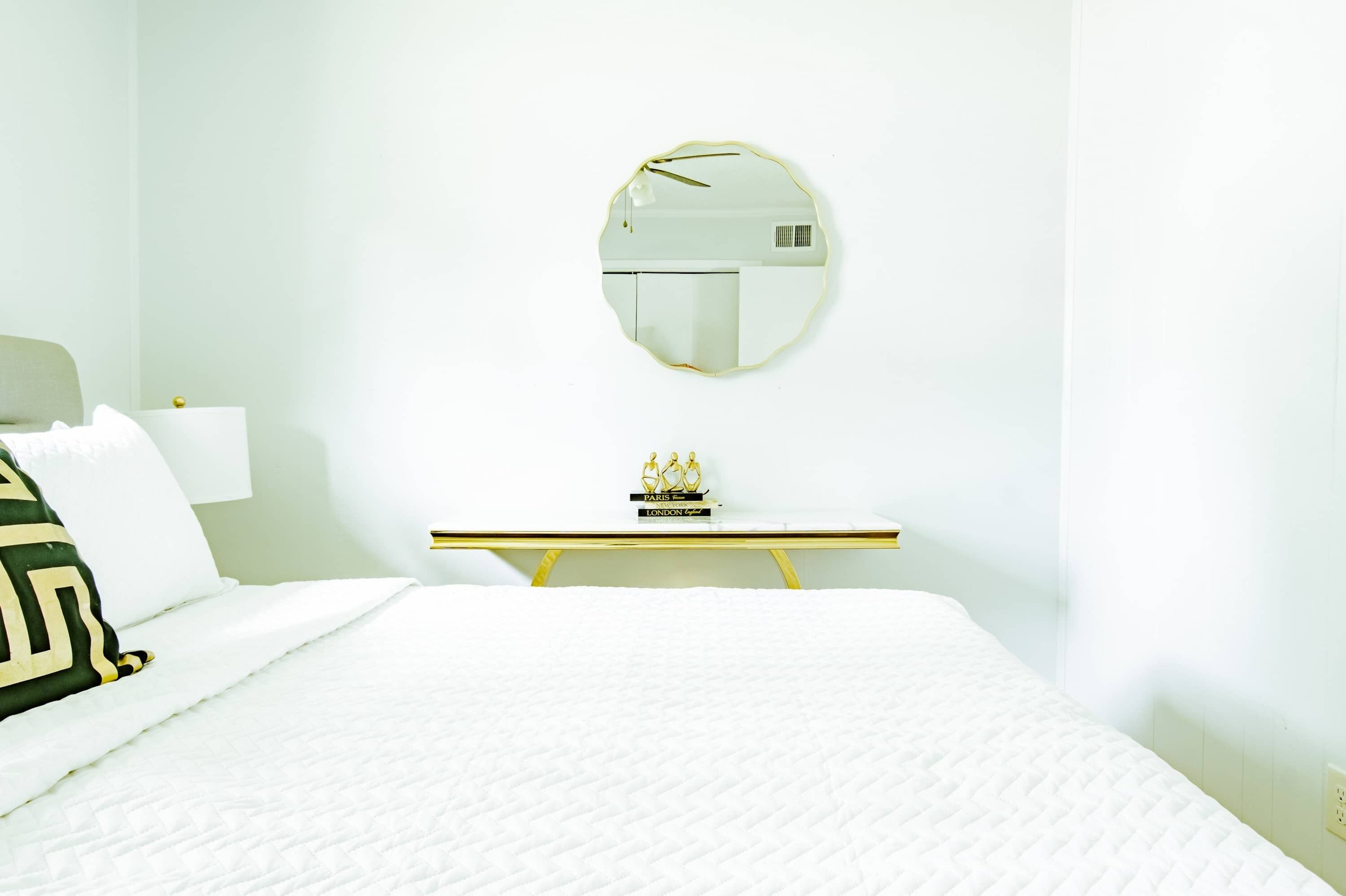 Une chambre d’hôtel avec un lit, une table de chevet, un miroir et un petit objet décoratif posé sur la table.