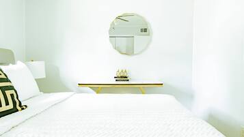 Une chambre d’hôtel avec un lit, une table de chevet, un miroir et un petit objet décoratif posé sur la table.