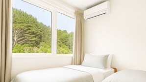 A bedroom with two beds, a window with curtains, and an air conditioning unit on the wall. - Skyline Sanctuary: Green View, Bird Songs, Parking, Espresso & Netflix (Wellington)