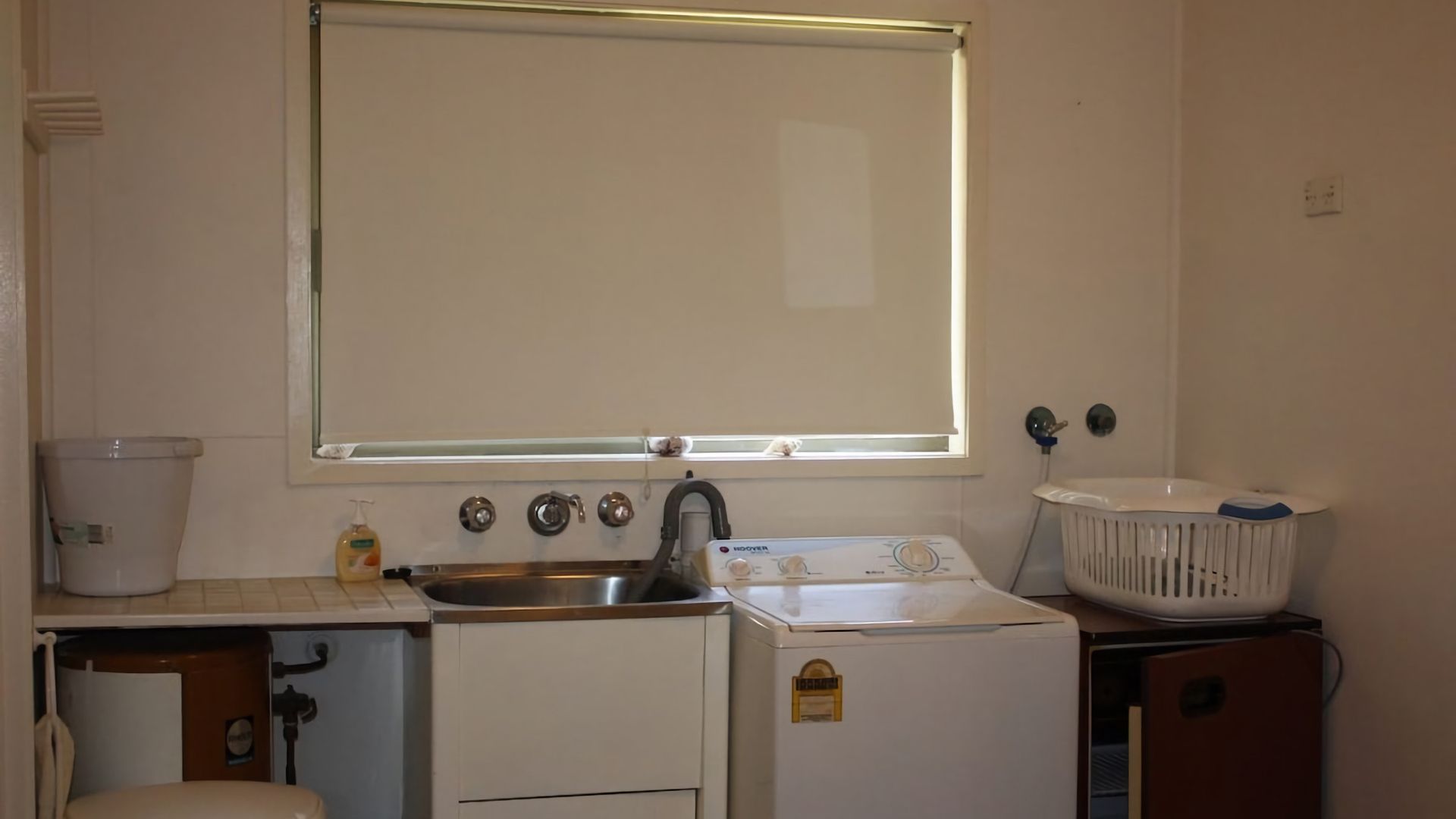 A compact kitchen with a sink, a washing machine, and a dryer.