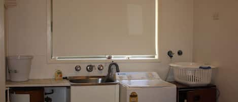 Une cuisine de taille réduite équipée d’un évier, d’un lave-linge et d’un sèche-linge.