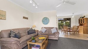 A living room with two sofas, a coffee table, and a dining area with chairs and a table. - Manyana Deck Life is a spacious pet friendly home (Manyana)