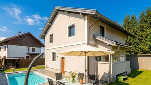 A two-story house with a swimming pool, outdoor dining area, and a covered patio.