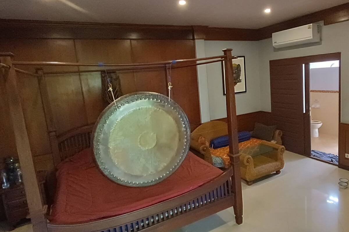 A traditional room with a four-poster bed, a small sofa, and a wooden cabinet.