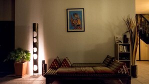 A cozy living area with a sofa, a floor lamp, a bookshelf, and a framed artwork on the wall. - Marissa Hotel (Ko Pha-ngan)