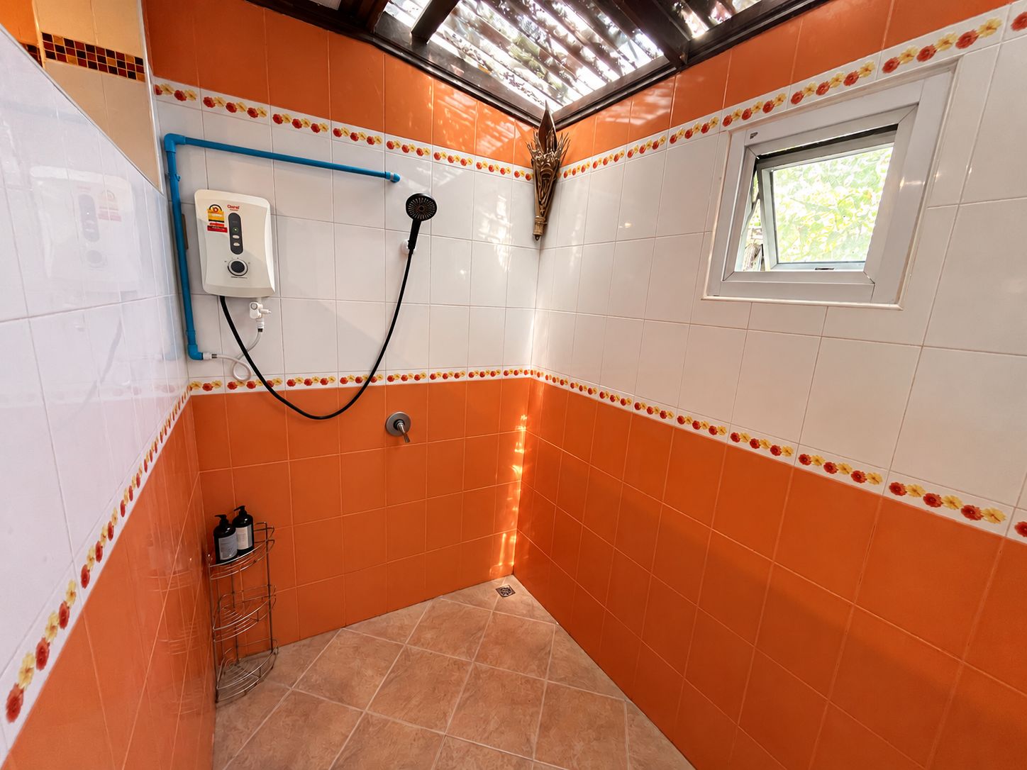 A bathroom with orange tiles, a shower, a window, and a towel rack.