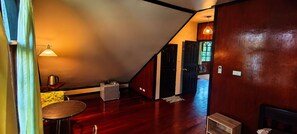 A room with a wooden floor, a small table, a chair, a lamp, and a door leading to another room. - Marissa Hotel (Ko Pha-ngan)