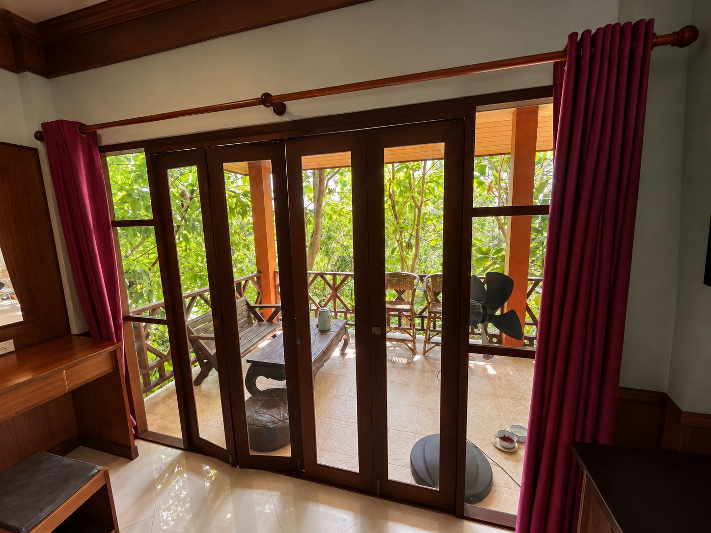 Une pièce dotée d’une porte-fenêtre coulissante donnant sur un espace extérieur aménagé avec du mobilier et de la verdure.