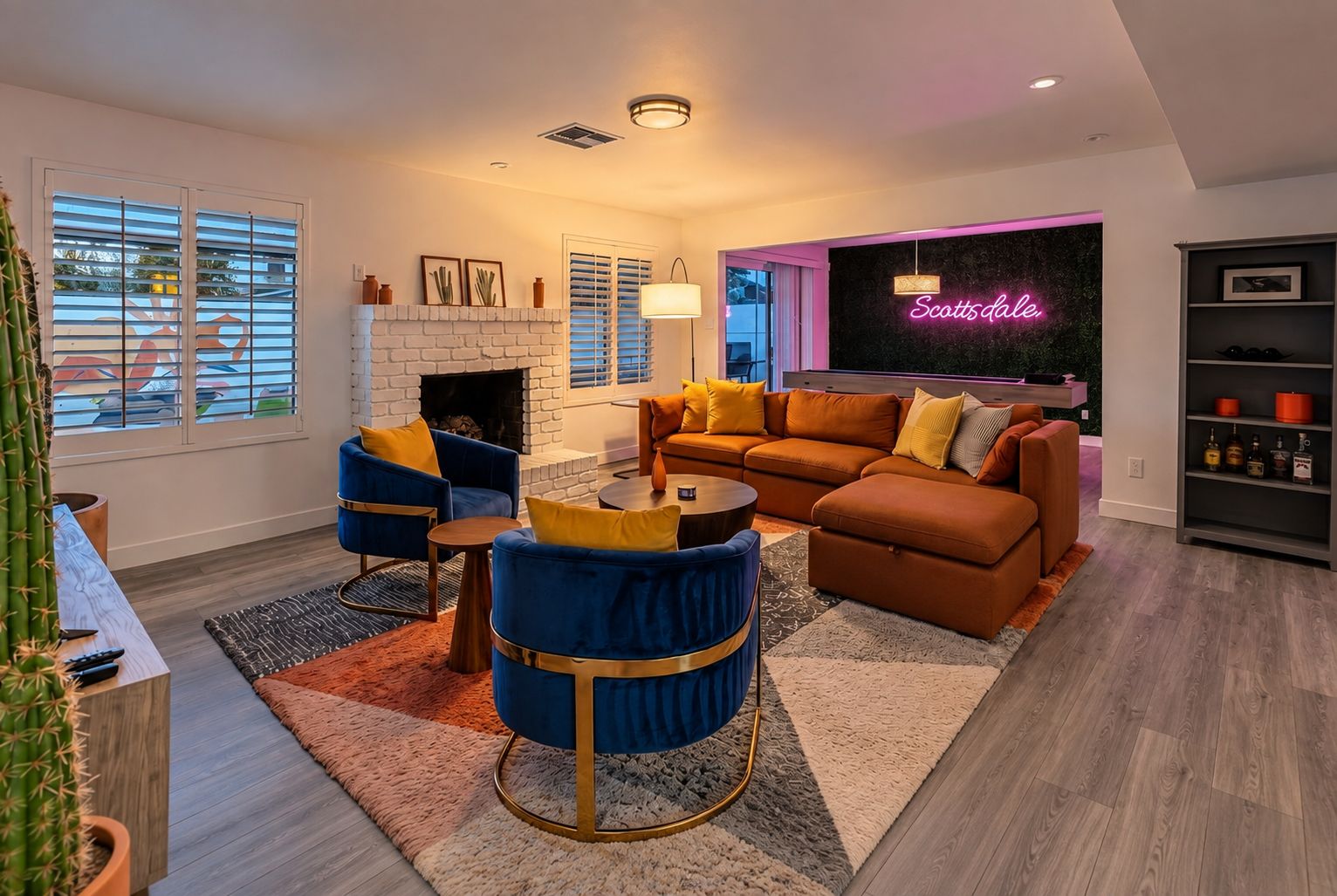 A modern living room with a fireplace, comfortable seating, and a neon sign.