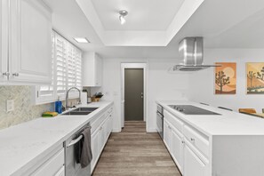 A modern kitchen with white cabinetry, a central island, and a herringbone-patterned backsplash. - Scottsdale Pool Home, Putting Green, Giant Chess & Shuffleboard Walk to Coffee (Scottsdale)