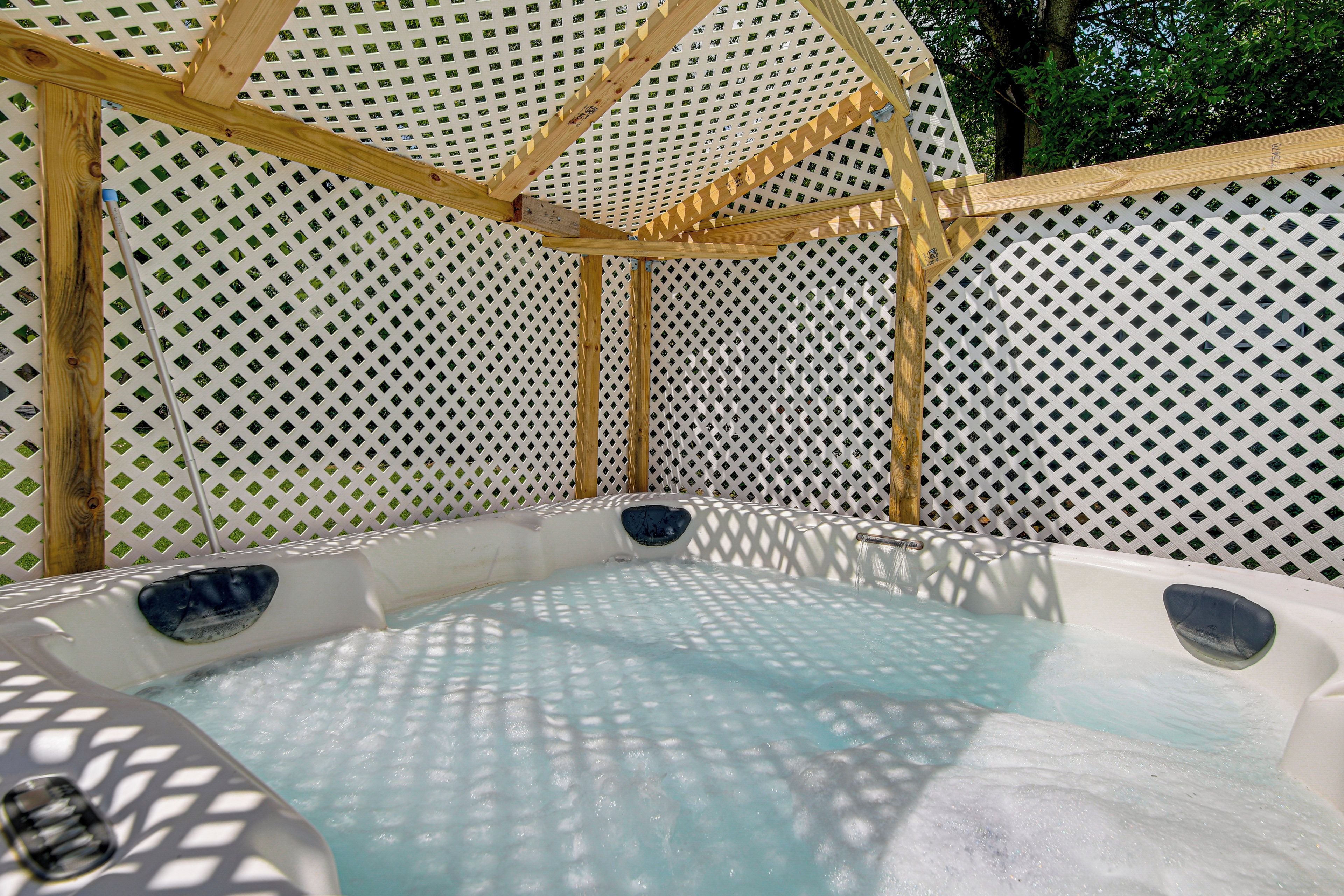 Een hottub met een houten omlijsting en een witte lattenwand.