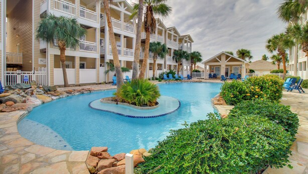 A hotel with a pool surrounded by palm trees and a stone deck. - Walk to Beach & Dining: Corpus Christi Townhome (Corpus Christi)