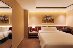 Una habitación de hotel con dos camas, una mesita de noche, una lámpara y cuadros en la pared.