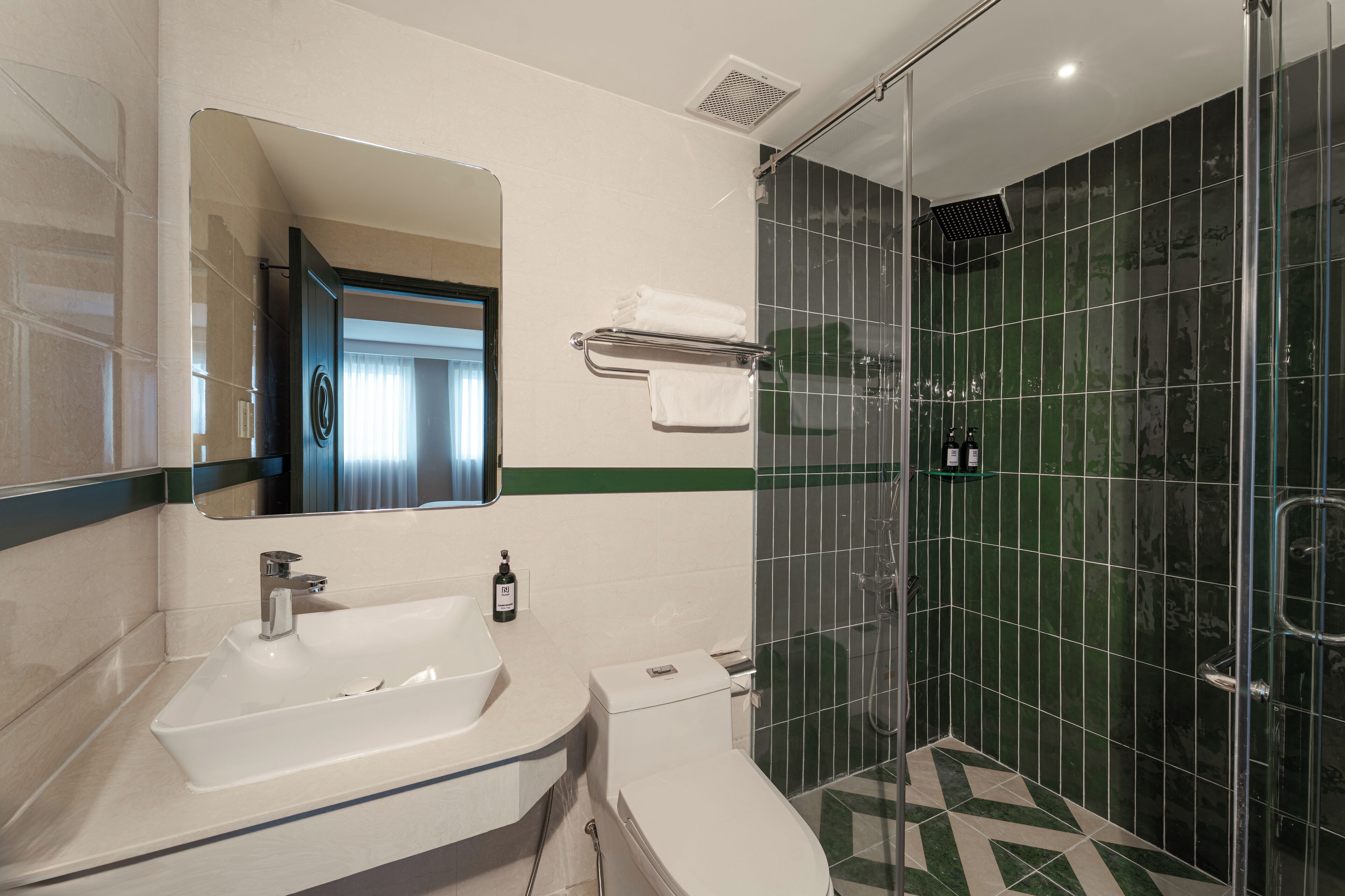 A bathroom with a white sink, a mirror, a toilet, and a glass-enclosed shower area.